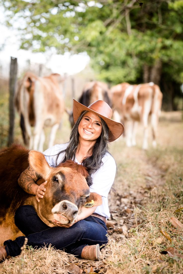 a woman in a cowboy hat is holding a cow