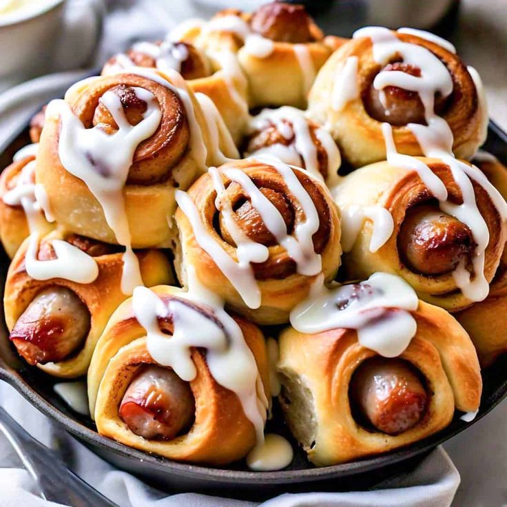 a plate full of hot dogs wrapped in cinnamon rolls and drizzled with icing