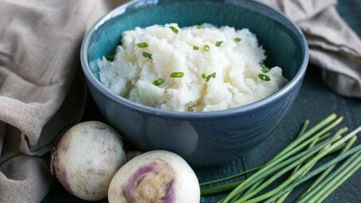 a blue bowl filled with mashed potatoes next to green onions