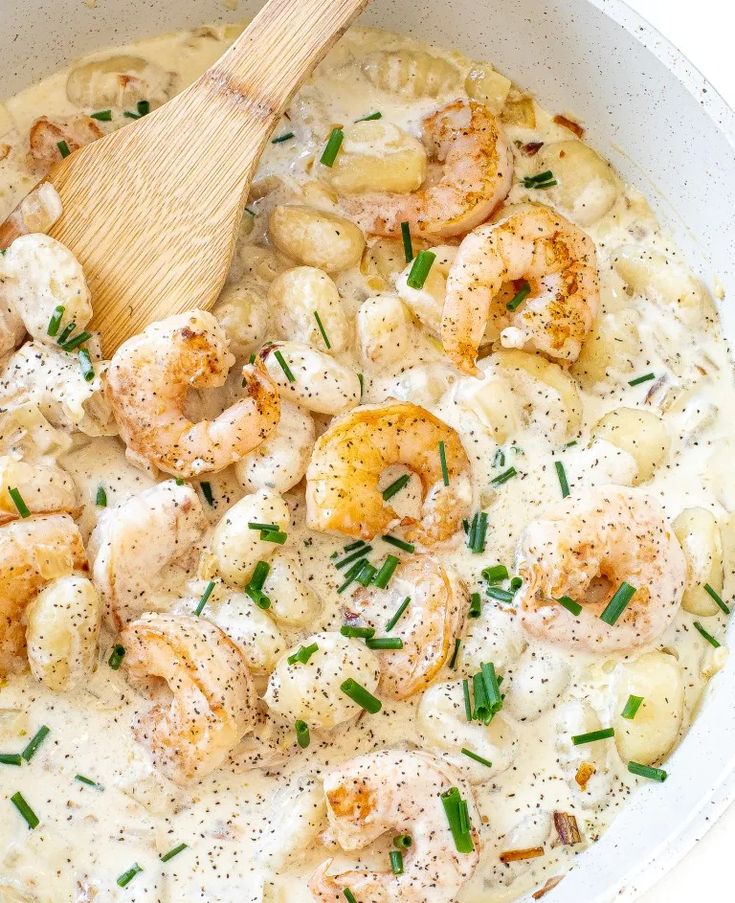 a white bowl filled with shrimp and grits on top of a wooden spatula