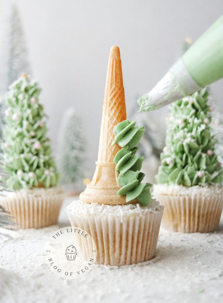 someone is decorating cupcakes with green frosting and an ice cream cone