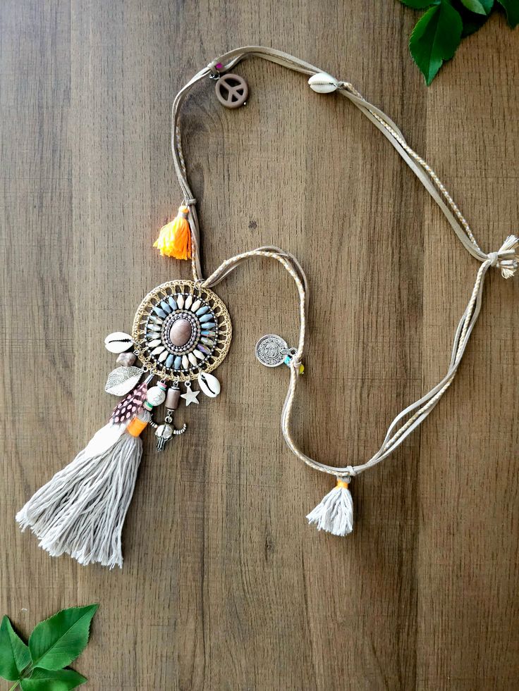 Embrace the beauty of bohemian style with this stunning handcrafted necklace. Featuring an intricate centerpiece adorned with seashells, tassels, and a blend of earthy tones, this piece evokes a free-spirited and natural vibe. The delicate details, such as charms, feathers, and beads, bring a sense of adventure and uniqueness to your look, perfect for those who love to express their individuality with their accessories." Bohemian Summer Strand Shell Necklace, Adjustable Tassel Necklace For Festivals, Bohemian Shell Necklace For Summer Beach, Bohemian Long Necklace With Tassels, Bohemian Adjustable Tassel Necklace For Festivals, Adjustable Bohemian Long Necklace With Tassels, Adjustable Bohemian Tassel Necklace For Festivals, Bohemian Multicolor Shell Necklace For Beach, Bohemian Multicolor Shell Necklace For Summer