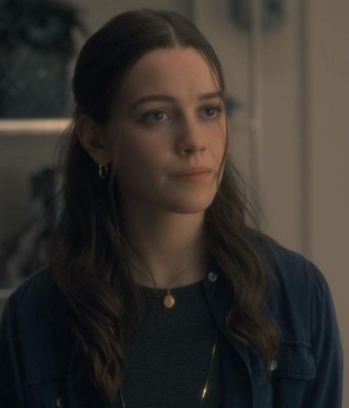 a woman with long hair wearing a black shirt and gold earring in a kitchen