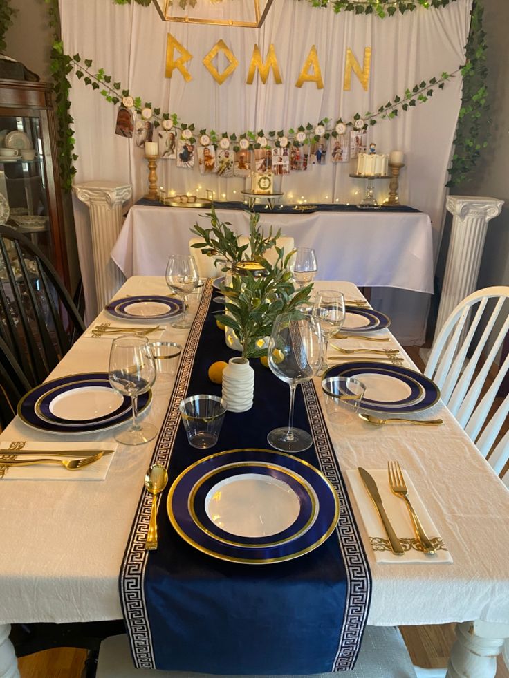 the table is set with blue and white plates, silverware, and greenery