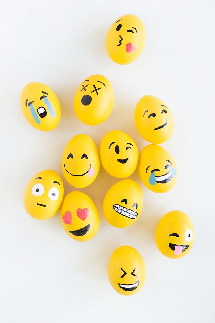 a bunch of yellow eggs with different faces painted on them, all arranged in the shape of smiley faces