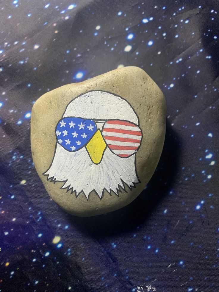 a rock with an eagle painted on it and stars in the sky behind it,