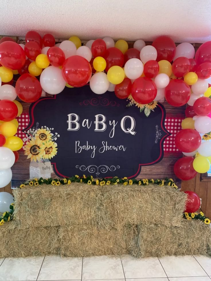 a baby shower sign surrounded by balloons and hay bales