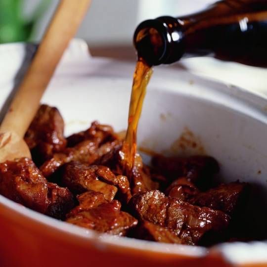 a bowl filled with meat and sauce being poured into it