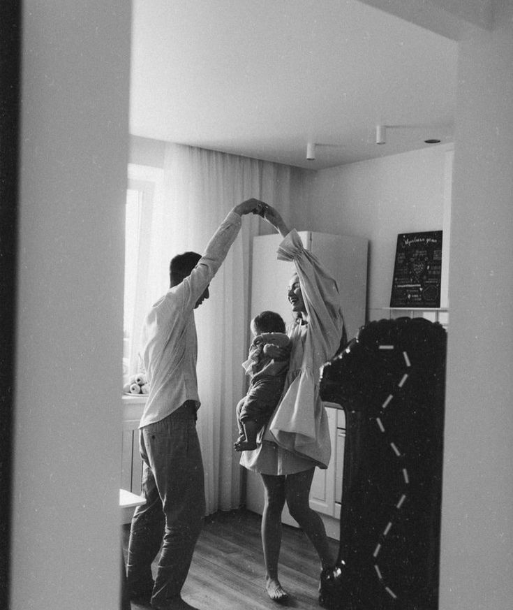 a man and woman standing in front of a mirror holding their arms up to each other