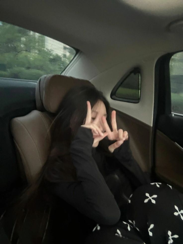 a woman sitting in the back seat of a car with her hands on her face