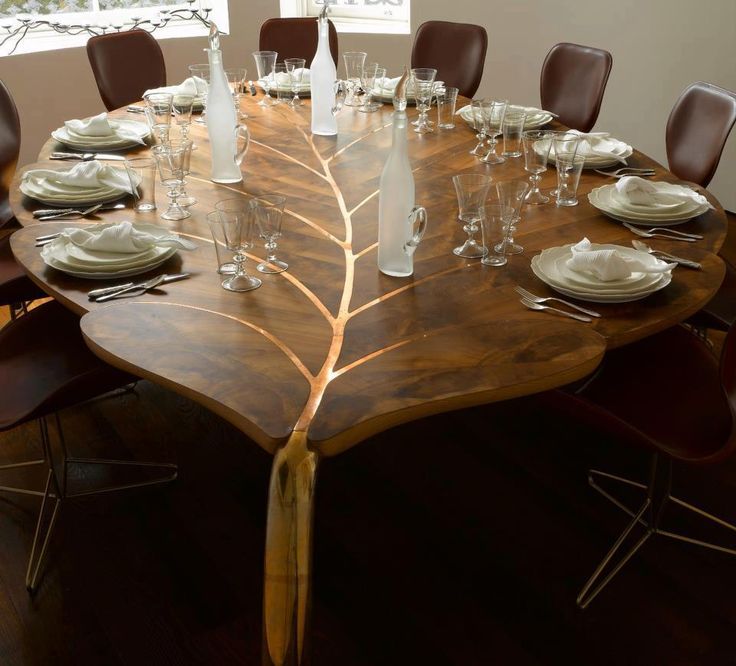 a large wooden table with white plates and wine glasses on it, in front of a window