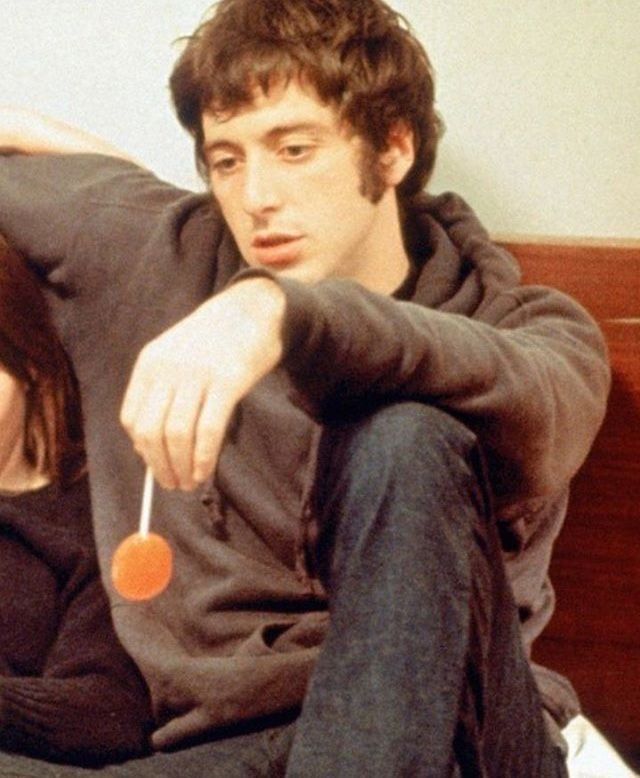 a man and woman sitting on a bed with an orange lollipop in their hand