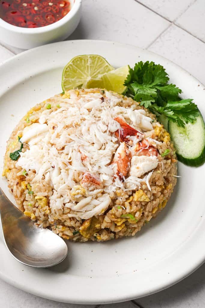 a white plate topped with rice and veggies next to a bowl of sauce