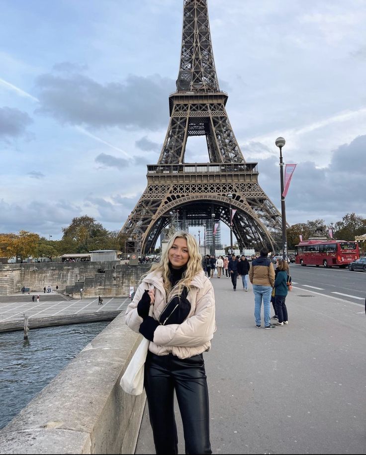 a woman is standing in front of the eiffel tower, posing for a photo