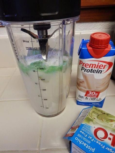 a blender filled with green liquid next to a carton of oatmeal