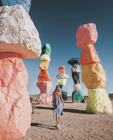 a person walking in front of large rocks with different colors and shapes on them,