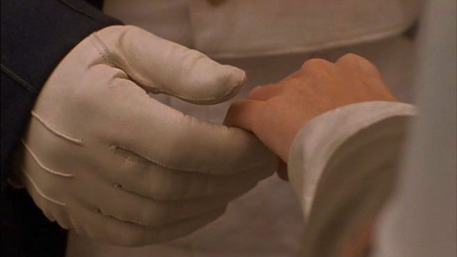 a close up of a person wearing white gloves and holding something in their hand with both hands