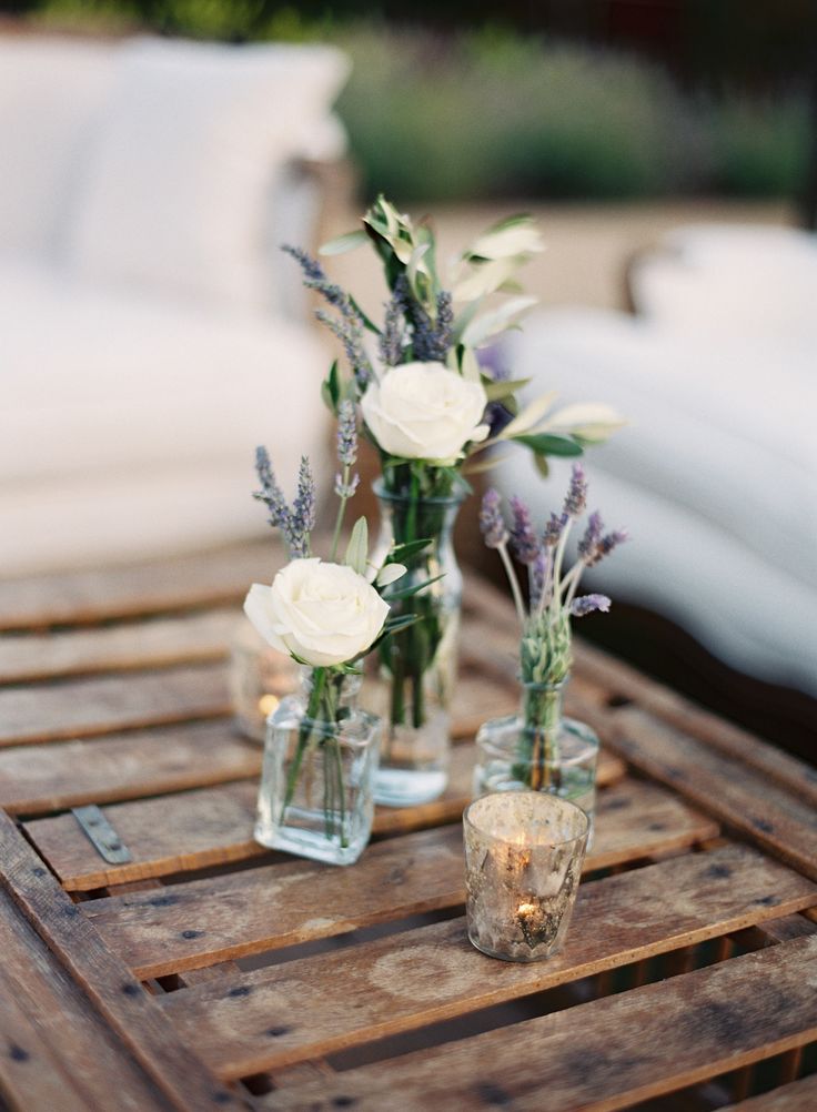 three vases with flowers are sitting on a wooden table in front of a couch