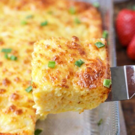 a close up of food on a pan with a spatula and strawberries in the background