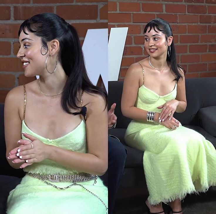 two women in dresses sitting on a couch and one is smiling at the other woman