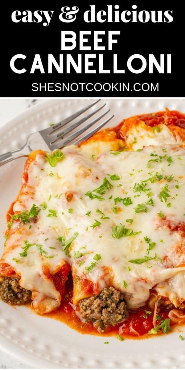 a white plate topped with lasagna covered in cheese and sauce next to a fork