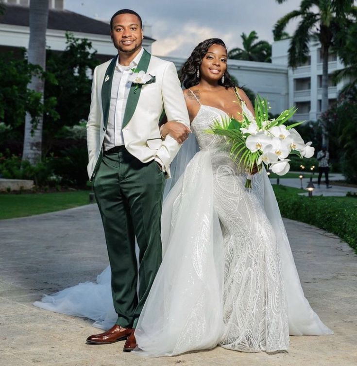 a man and woman in wedding attire walking down the street with palm trees behind them