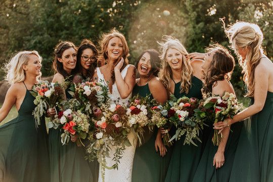 a group of women standing next to each other with bouquets in their hands and smiling at the camera