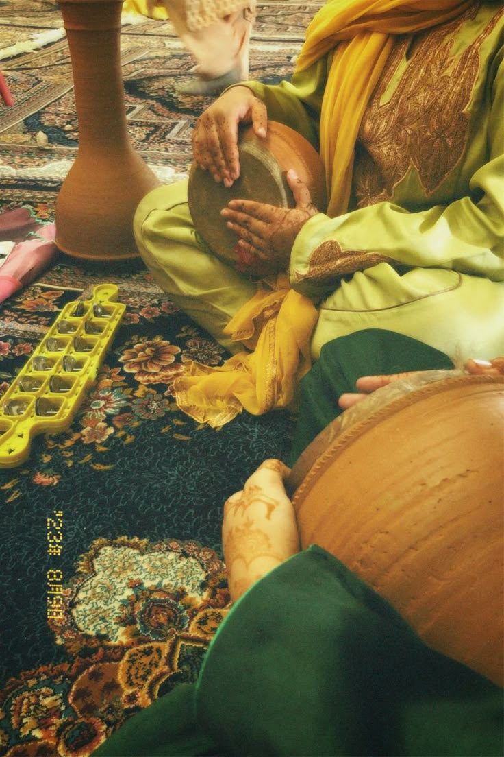 a woman sitting on the floor playing with a drum