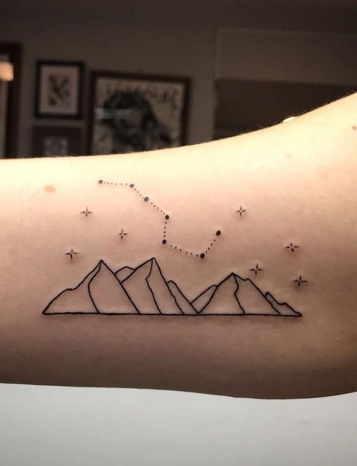 a man's arm with mountains and stars on it