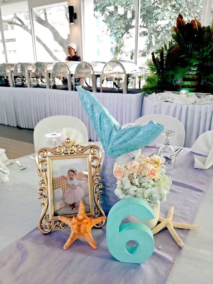 the table is set up for a wedding reception with pictures and flowers on it, along with starfish decorations