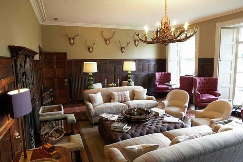 a living room filled with lots of furniture and a chandelier hanging from the ceiling