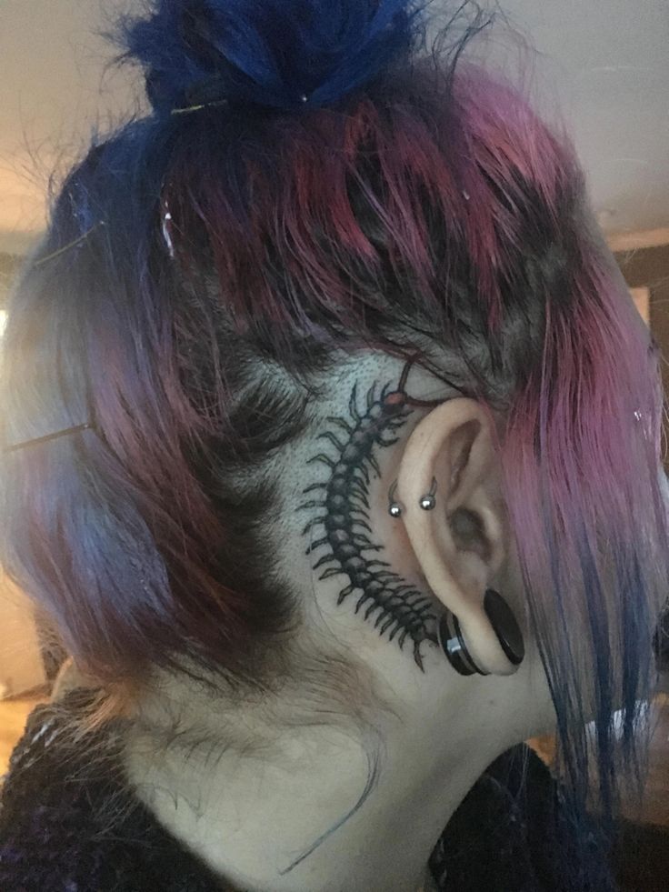 the back of a woman's head with colorful hair and tattoos on her face