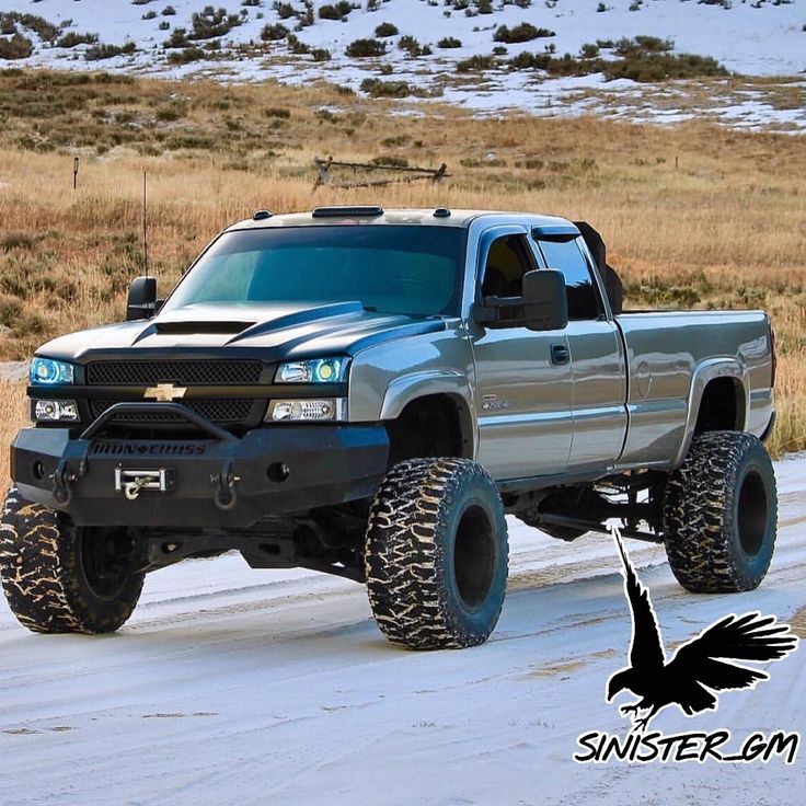 a silver truck driving down a snow covered road