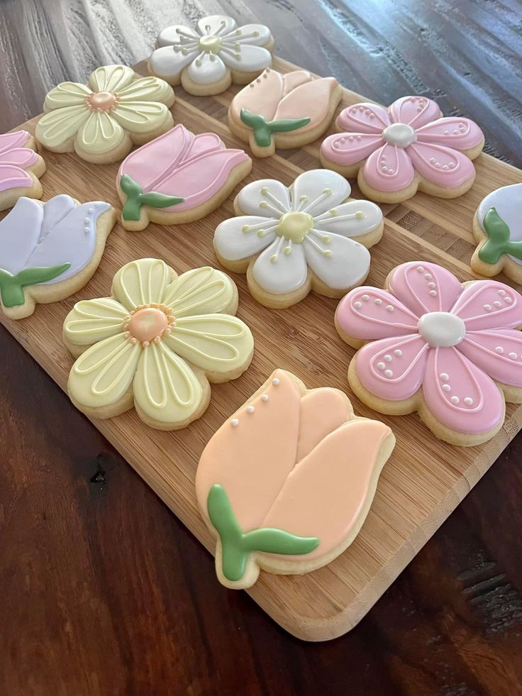 decorated cookies are arranged on a cutting board, ready to be cut into flowers and butterflies