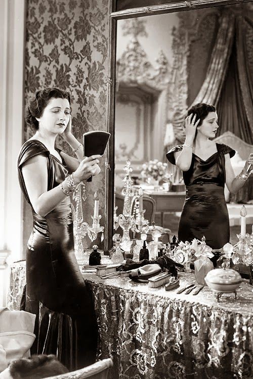 an old photo of two women in front of a mirror