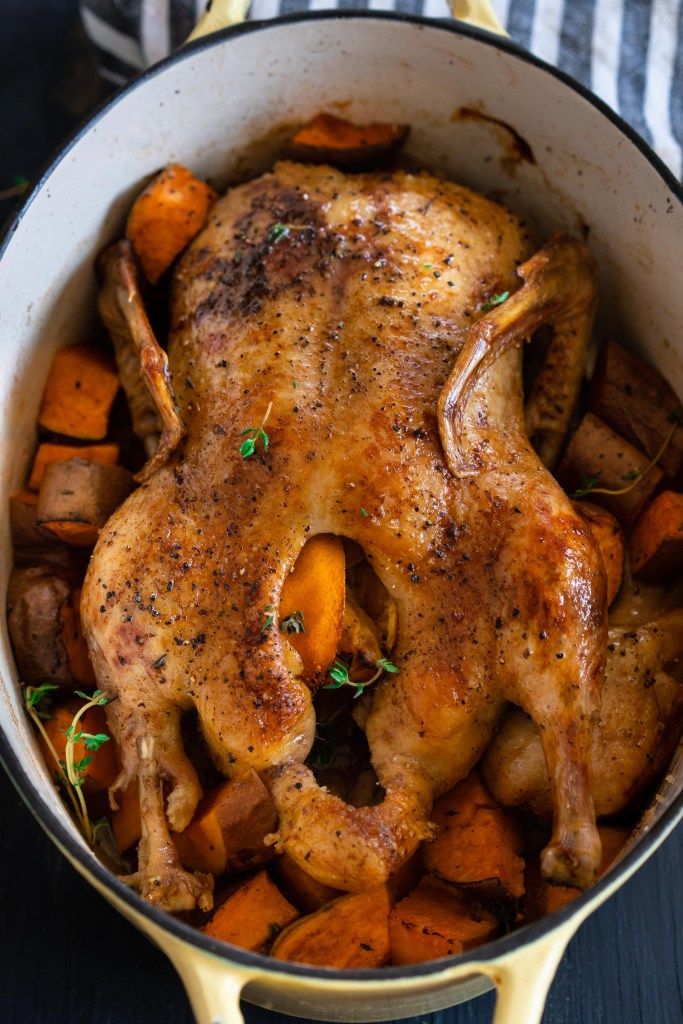 a whole chicken in a pot with carrots and potatoes