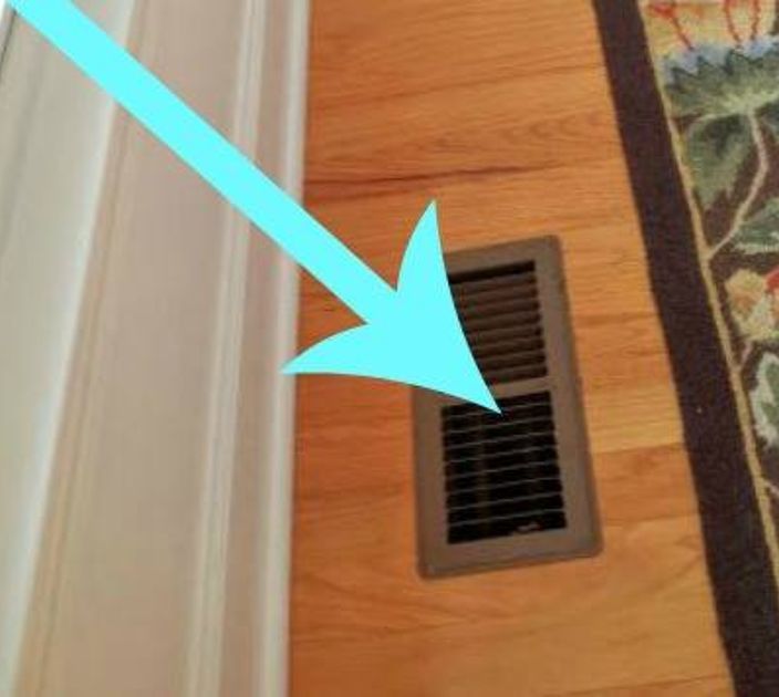 an air vent is on the floor next to a rug with flowers and blue arrow pointing up