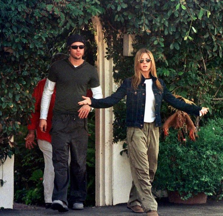 a man and woman are walking down the street holding their hands out to each other