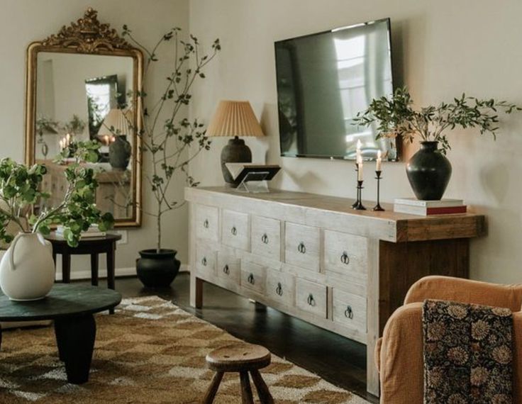 a living room filled with furniture and a flat screen tv on top of a wooden dresser