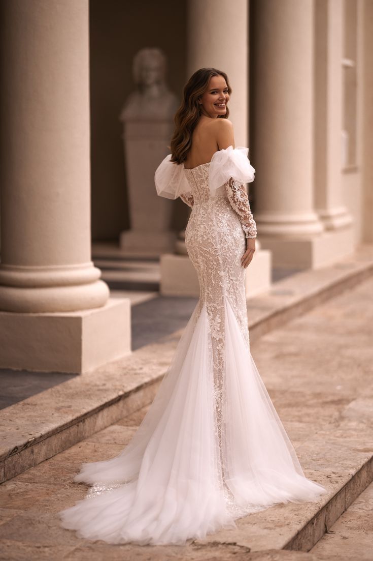 a woman in a white wedding dress standing on some steps with her back to the camera