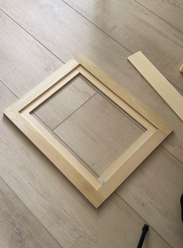 a wooden frame sitting on top of a hard wood floor next to a pair of scissors