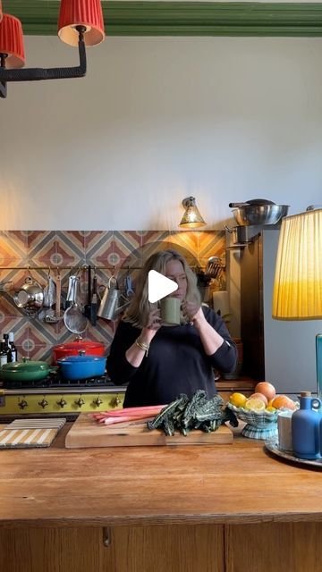 a woman standing in front of a kitchen counter holding a cup with food on it