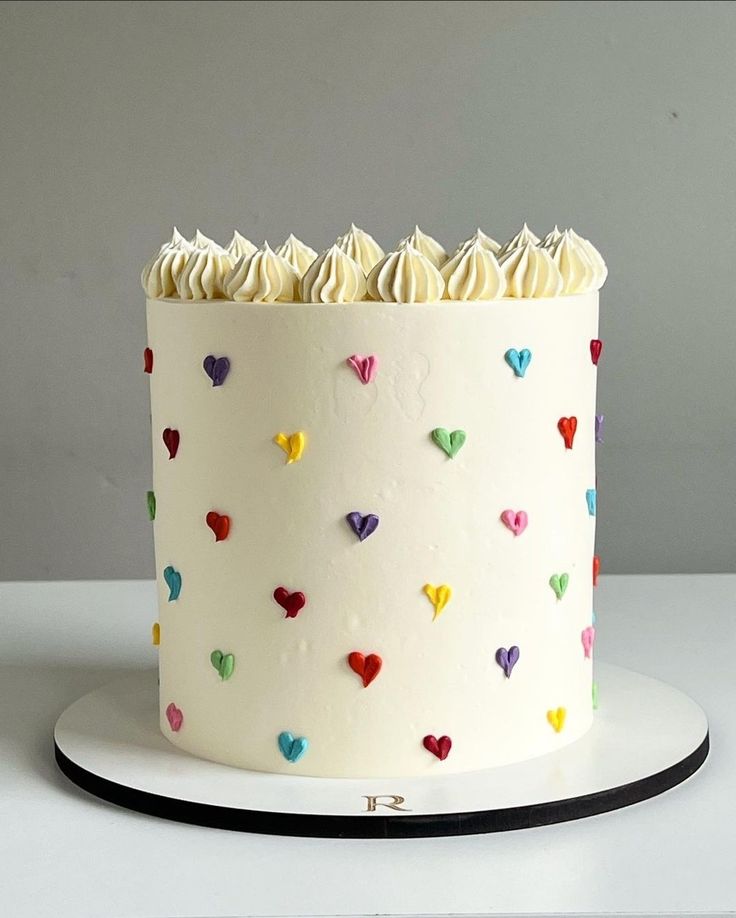 a white cake with multicolored hearts on it