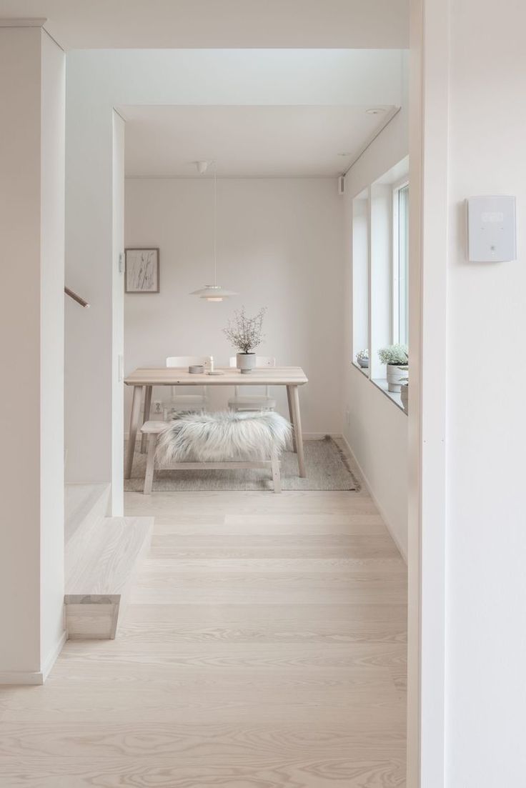 an open door leading to a white room with a table and bench in the background