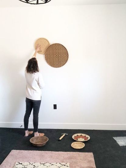 a woman standing in front of a wall with plates and bowls on the floor next to it