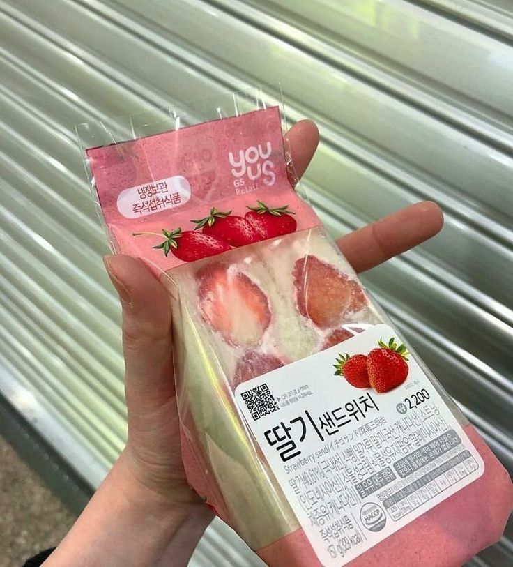 a person holding up a package of frozen strawberries in front of a metal wall