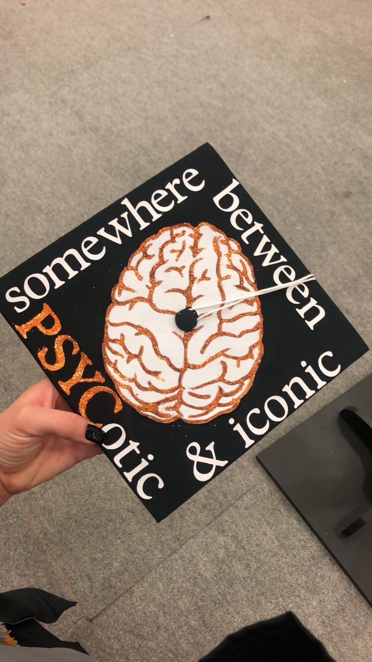 someone is holding up a graduation cap that has a brain on it and the words somewhere between psychic & ironic