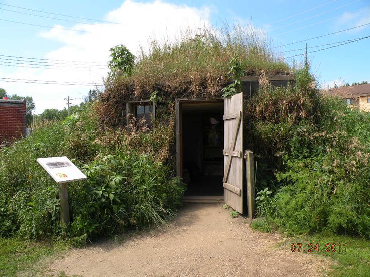 the entrance to an old building with grass growing on it's roof and door