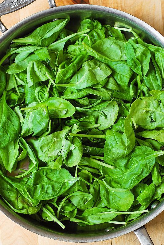 a pot filled with spinach on top of a wooden table