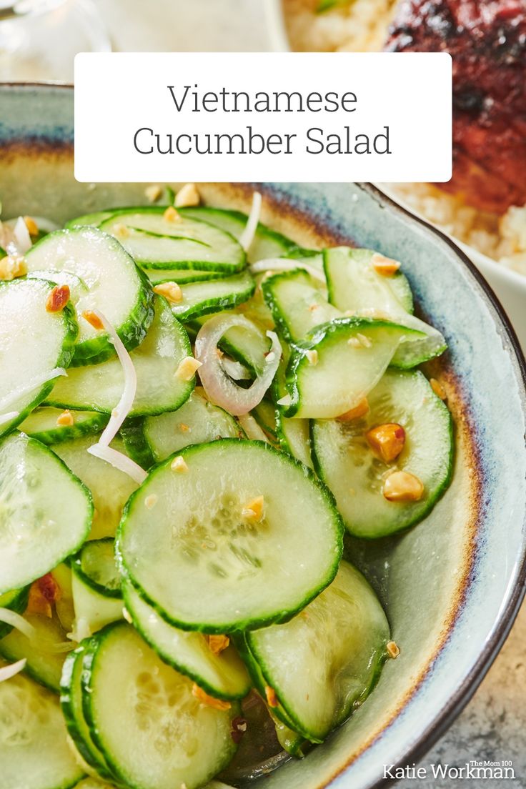 a bowl filled with cucumber salad on top of a table next to rice